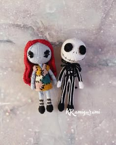 two crocheted dolls sitting next to each other on a white surface with snow flakes