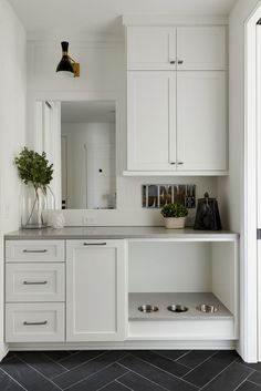 a kitchen with white cabinets and black tile flooring