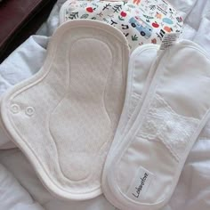 three baby bibs laying on top of a bed