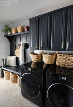 a black washer and dryer in a room with baskets on the back wall