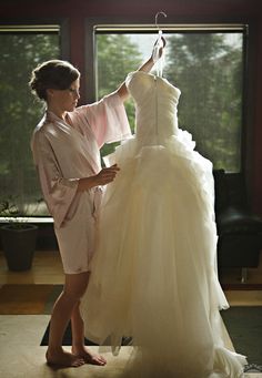 the bride is trying on her wedding dress