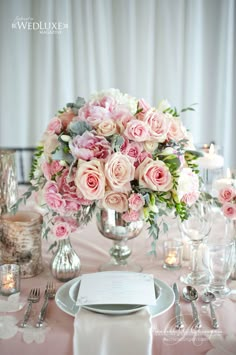 a table set with pink flowers and silverware