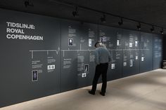 a man standing in front of a black wall with white writing and pictures on it