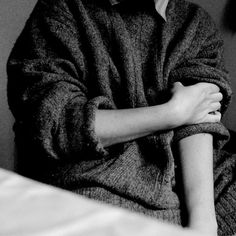 a young man sitting on top of a bed next to a wall with his arms crossed