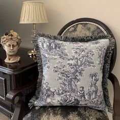 a chair with a pillow on top of it next to a busturine and lamp