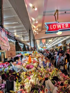 a bunch of flowers that are on display in a store with people looking at them