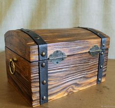 a wooden box with metal straps on it sitting on a table next to a wall