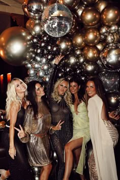 several women posing for the camera with disco balls in the background