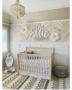 a baby's room with a white crib and wooden name sign on the wall