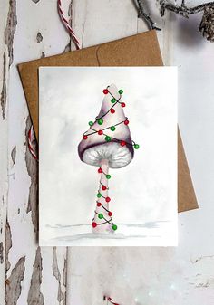 a card with a mushroom on it and christmas lights hanging from the top, next to some candy canes