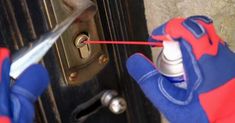 a person in blue and red gloves using a screwdriver to open a door