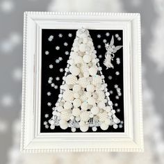 a christmas tree made out of white balls and beads is displayed in a framed frame