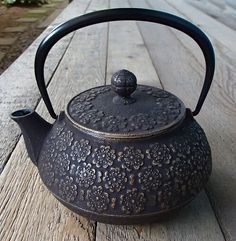 an iron tea pot sitting on top of a wooden table