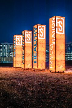 there are four tall orange boxes with words on them in the middle of a field