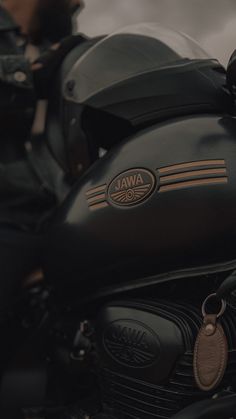 a close up of a black motorcycle parked on the side of the road with clouds in the background