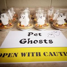 a sign that says pet ghost's open with caution next to some glass cups filled with candy