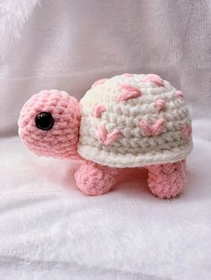 a crocheted turtle with a hat on it's head sitting on a white blanket