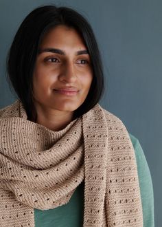 a woman wearing a knitted scarf and smiling at the camera