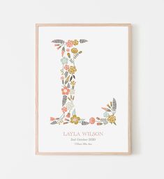 the letter l is made up of colorful flowers and leaves on white paper with a wooden frame