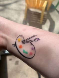 a person's arm with a tattoo on it that has an arrow and paint splattered on it