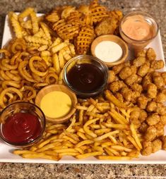 a plate full of fries and dipping sauces