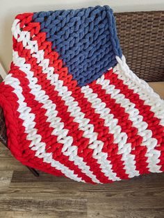 a red, white and blue crocheted blanket sitting on top of a chair