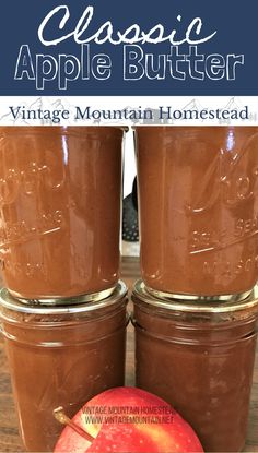 two jars filled with chocolate apple butter sitting on top of a wooden table next to an apple