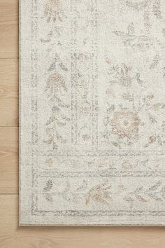 a white rug with an intricate design on the top and bottom, sitting on a wooden floor