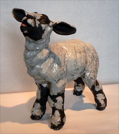 a ceramic figurine of a sheep standing on a table next to a wall