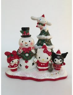 a group of hello kitty figurines sitting on top of a snow covered ground