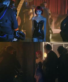 some people are standing around and one is wearing a black latex outfit while the other has red hair