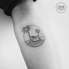 a black and white photo of a palm tree tattoo on the right inner arm, with an ocean view in the background