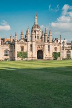 an old building with a clock tower on the top and green grass in front of it