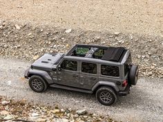 a jeep is parked on the side of a dirt road near some rocks and gravel