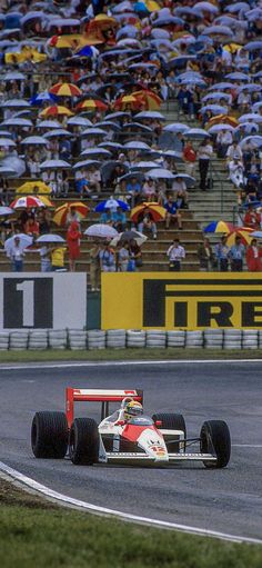 a man driving a race car down a track with an audience watching from the stands