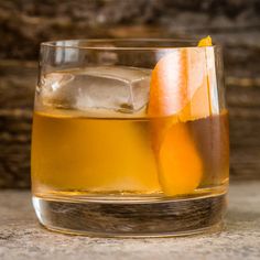 a glass filled with liquid sitting on top of a table next to an orange slice