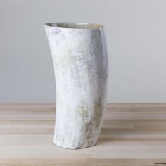 a white vase sitting on top of a wooden table