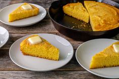 four plates with slices of cornbread on them and one slice has butter in it