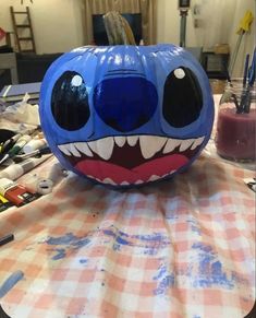 a blue pumpkin with teeth painted on it sitting on a table next to other items