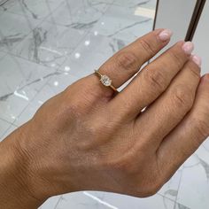 a woman's hand with a diamond ring on top of her left hand and a mirror in the background