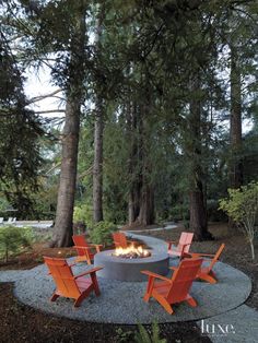 an outdoor fire pit surrounded by chairs and trees