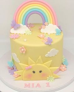 a yellow cake with a rainbow and clouds on it