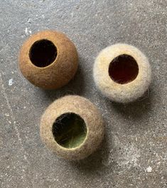 three wool balls with holes in them sitting on the ground