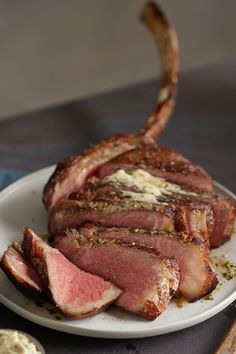 some meat is on a white plate with sauce and seasoning next to other food items