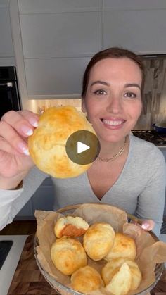 a woman holding up a bowl filled with bread