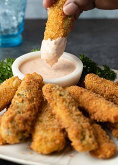 a person dipping sauce on some fried food