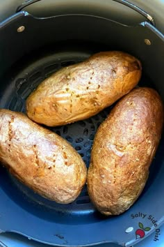 three baked potatoes in an air fryer basket