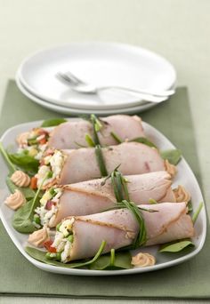 a white plate topped with slices of ham covered in veggies and sauces