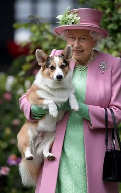 the queen is holding a dog in her arms