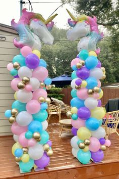 two unicorn balloons are sitting on the back of a wooden table in front of a house